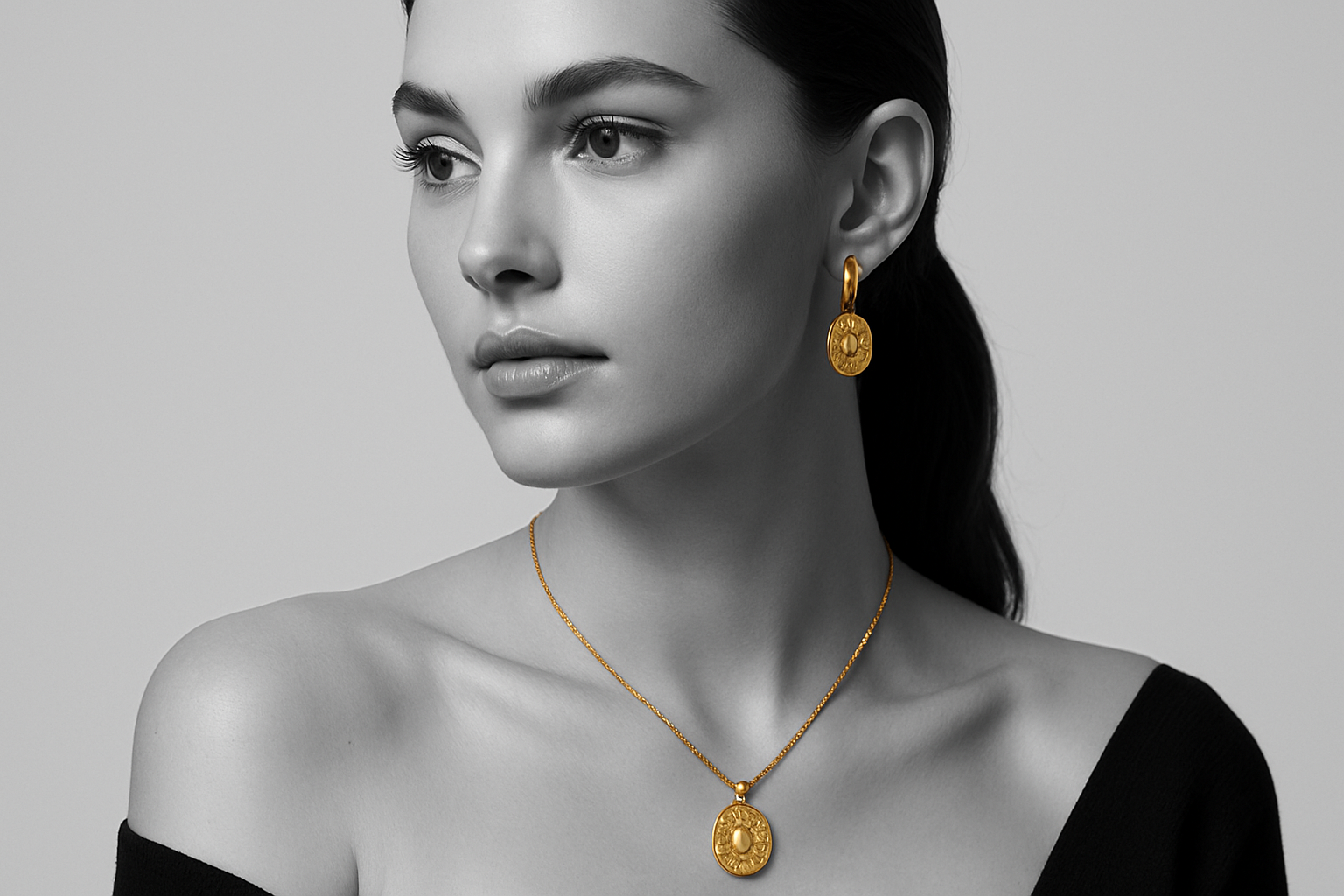 A black-and-white luxury catalogue-style photo of a woman wearing a gold-plated pendant necklace and matching earrings. The jewellery shines in rich golden tones while the rest of the image stays in monochrome. Clean background, soft studio lighting, focus on jewellery details